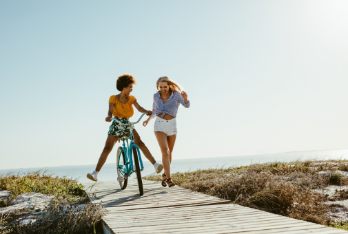 Two women having fun at the beach on a bike. 